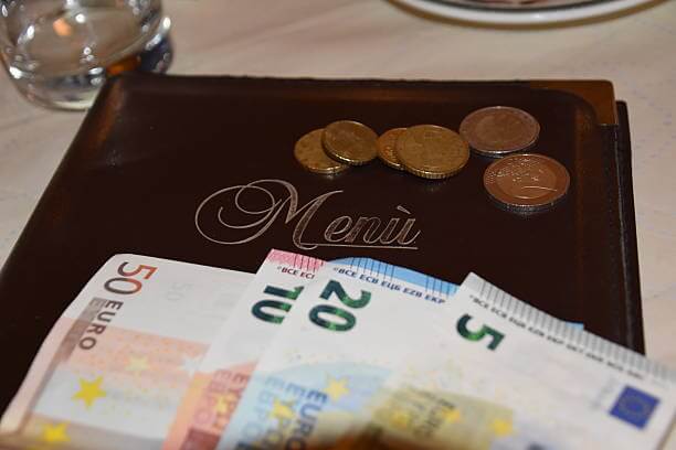 Tipping in Rome — coins and bill left on a café table in Italy, showing local tipping etiquette.