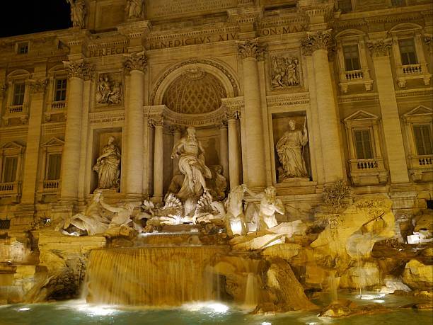 Trevi Fountain glowing at night with cascading water and Baroque sculptures.