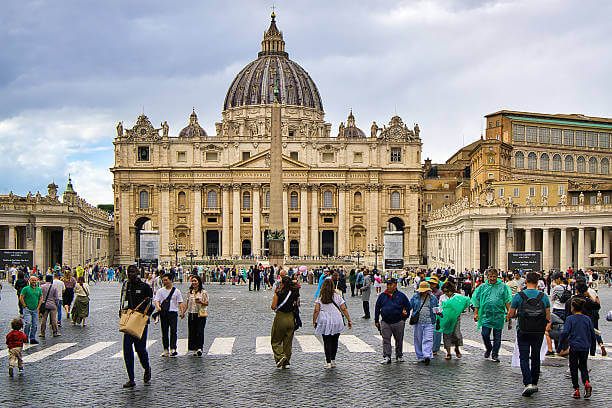 A wide shot of St. Peter’s Basilica façade with visitors in St. Peter’s Square
