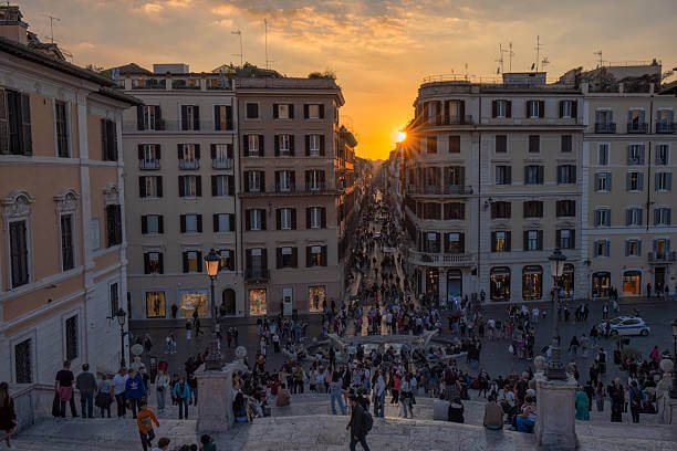 Spanish Steps in Rome at sunset with warm golden-hour light and visitors sitting on the staircase