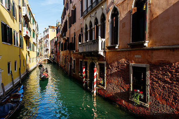 Traditional gondola gliding through a narrow canal in Venice.