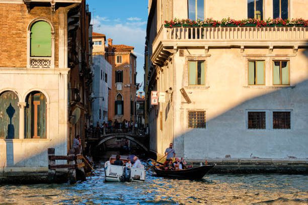 Traditional gondola gliding through narrow canal in Venice Italy at golden hour