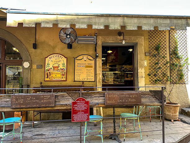 authentic Tuscan trattoria interior with wooden tables, Chianti bottles and handwritten menu on chalkboard