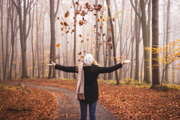 What to wear in Italy in October woman in layered autumn outfit walking cobblestone streets in Florence with golden leaves