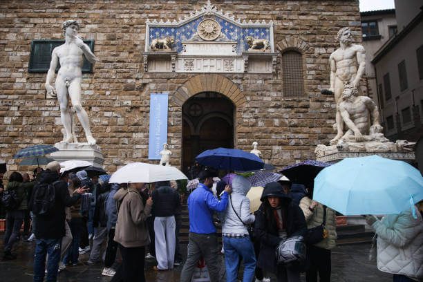 Accademia Best Guided Tours in Florence for Solo Travelers with small group standing before Michelangelo's David with expert guide