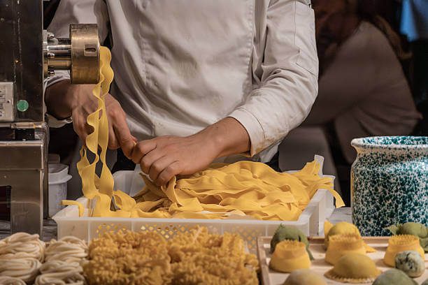 Florence cooking class for solo travelers solo traveler making fresh pasta at a communal cooking table with a Florentine chef instructor