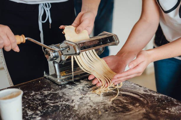  Best solo social activity in Florence solo traveler making fresh pasta at a communal cooking table in a Florentine cooking class with other travelers
