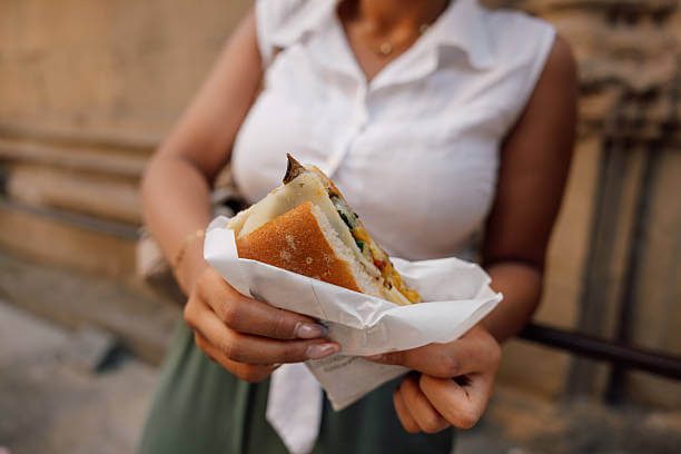 Florence solo traveler eating a lampredotto tripe sandwich standing at a traditional Florentine trippai cart
